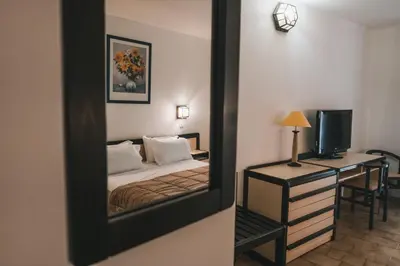 a mirror in a room with a bed and a desk at Hôtel & Résidence Le Subrini in Porto Ota