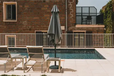 an umbrella and chairs next to a swimming pool at Hôtel & Résidence Le Subrini in Porto Ota