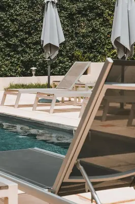 a group of chairs and umbrellas next to a pool at Hôtel & Résidence Le Subrini in Porto Ota