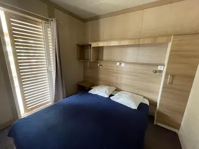 a bedroom with a blue bed and a window at Camping Trinité in Bonifacio