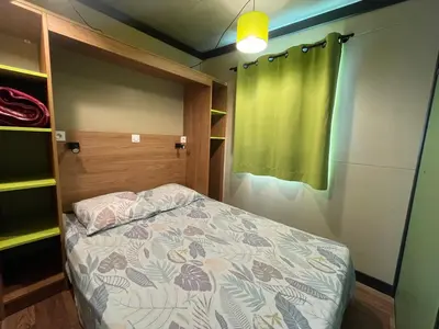 a small bedroom with a bed and a green curtain at Camping Trinité in Bonifacio