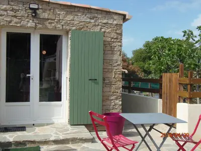 a patio with a table and chairs and a door at mini villa Marcel classée 3 étoiles in Calenzana