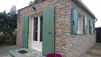 a stone building with green shutters and a door at mini villa Marcel classée 3 étoiles in Calenzana