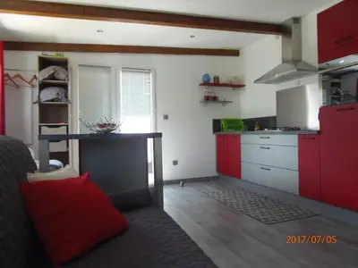 a kitchen with red cabinets and a couch in a room at mini villa Marcel classée 3 étoiles in Calenzana