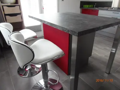 a kitchen with a red island with four white bar stools at mini villa Marcel classée 3 étoiles in Calenzana