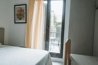 a bedroom with a bed and a window with a balcony at Hôtel Idéal in Porto Ota