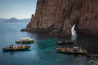 three boats in a body of water next to a mountain at Hôtel Idéal in Porto Ota