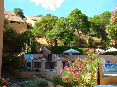 a view of a garden with flowers and umbrellas at Résidence Cabanaccia in Serriera