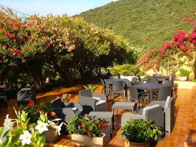 a patio with tables and chairs and flowers at Résidence Cabanaccia in Serriera