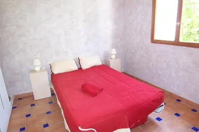 a red bed in a small room with two lamps at Andre in Porto-Vecchio