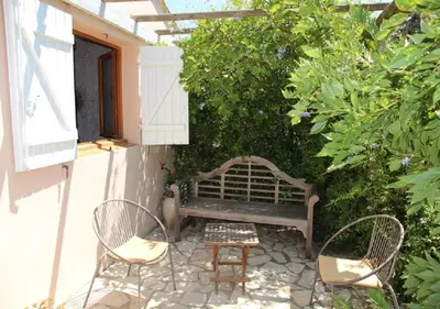 a patio with a bench and two chairs at Andre in Porto-Vecchio