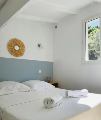 a white bedroom with a bed with towels on it at Propriété Malva appartement margherita in Alata