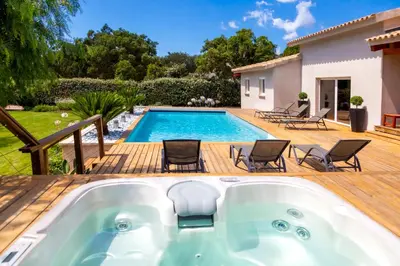a hot tub on a deck next to a swimming pool at Villa ARCA in Porto-Vecchio