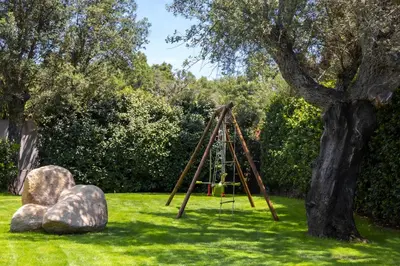a swing set in the grass next to a tree at Villa ARCA in Porto-Vecchio