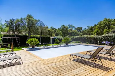 a swimming pool with chairs and a wooden deck at Villa ARCA in Porto-Vecchio