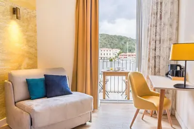a living room with a chair and a table and a window at Best Western Hotel du Roy d'Aragon in Bonifacio