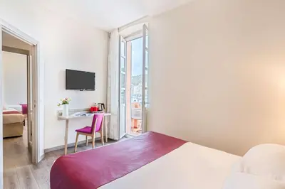 a hotel room with a bed and a desk and a window at Best Western Hotel du Roy d'Aragon in Bonifacio