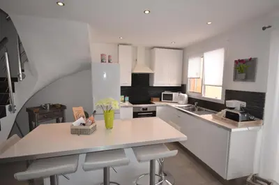 a kitchen with white cabinets and a counter with stools at Maison porto vecchio - lecci in Porto-Vecchio