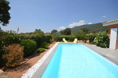 a swimming pool with two chairs in a garden at Maison porto vecchio - lecci in Porto-Vecchio