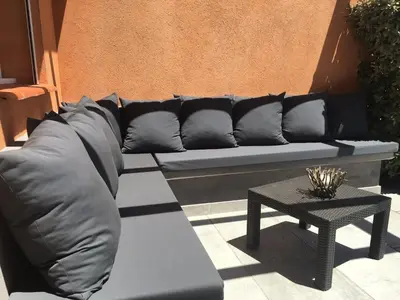 a black couch sitting on a patio with a table at Maison porto vecchio - lecci in Porto-Vecchio