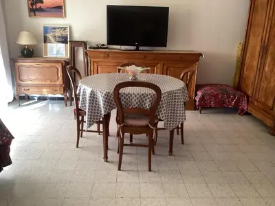 a dining room with a table with chairs and a television at Pietralba Saint Joseph in Ajaccio