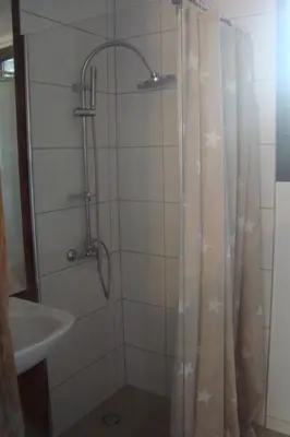 a shower with a shower curtain next to a sink at Rustica in Prunete