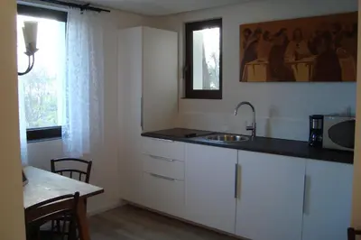 a kitchen with white cabinets and a sink and a table at Rustica in Prunete