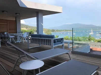 a deck with chairs and tables and a view of the water at Residence Capriona in Porto Pollo