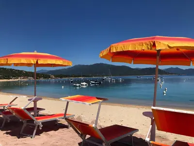 a group of chairs and tables on a beach with umbrellas at Residence Capriona in Porto Pollo
