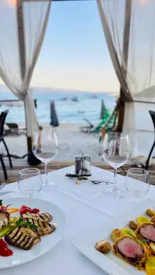 a table with two plates of food and wine glasses at Palm Beach in Ajaccio