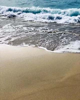 a sandy beach with waves crashing on the ocean at Palm Beach in Ajaccio