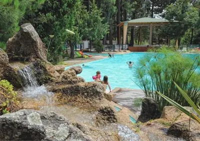 a pool with a waterfall and people playing in it at Camping Mulinacciu in Lecci
