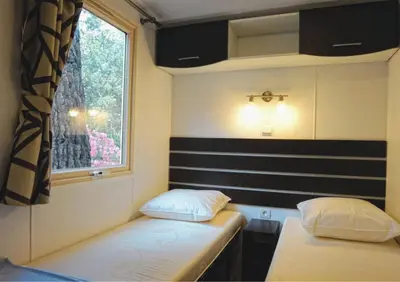 a small room with two beds and a window at Camping Mulinacciu in Lecci