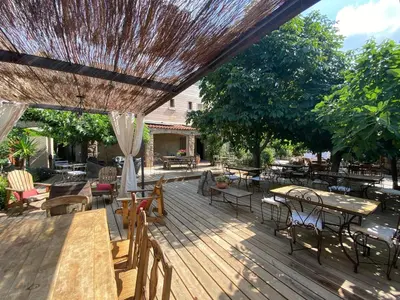 a wooden deck with tables and chairs and an umbrella at Hotel gite d'etape San Pasquale in Conca