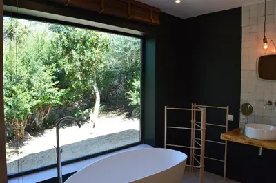 a bathroom with a large window and a tub at Les Petites Maisons in Sotta