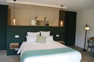 a bedroom with a large bed with a green wall at Les Petites Maisons in Sotta