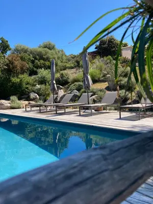 a swimming pool with lounge chairs and umbrellas at Les Petites Maisons in Sotta