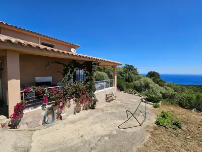 a house with flowers and a view of the ocean at Sari- Vue mer- climatisation in Sari Solenzara
