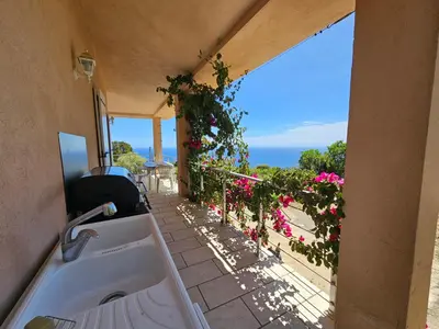 a kitchen with a view of a balcony with flowers at Sari- Vue mer- climatisation in Sari Solenzara