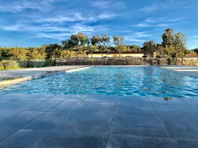 a swimming pool with blue water in a yard at Bonifacio 5 minutes du port et plage - clim & piscine in Bonifacio