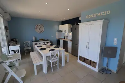 a kitchen with a table and chairs and a kitchen with blue walls at Bonifacio 5 minutes du port et plage - clim & piscine in Bonifacio