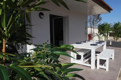 a white table and chairs on a patio with plants at Bonifacio 5 minutes du port et plage - clim & piscine in Bonifacio