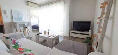 a living room with a white couch and a tv at Appartement Ajaccio vue mer panoramique in Ajaccio