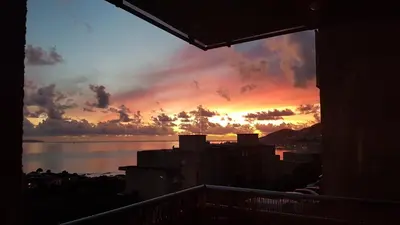 a view of a sunset from the balcony of a building at Appartement Ajaccio vue mer panoramique in Ajaccio