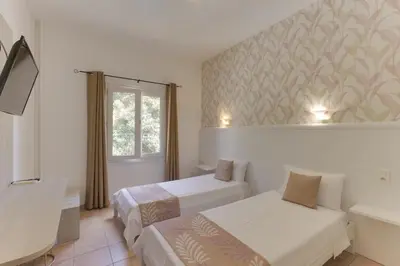 a hotel room with two beds and a window at Hotel des Etrangers in Bonifacio