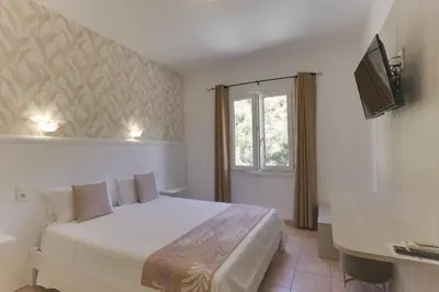 a bedroom with a white bed and a window at Hotel des Etrangers in Bonifacio