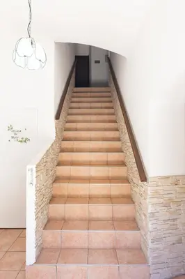 a staircase with wooden floors and a chandelier at Hotel des Etrangers in Bonifacio