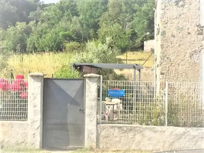 a fence with a door in front of a building at Casa Orani in Ponte-Leccia