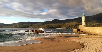 a lighthouse on a beach next to the water at Magnifique appartement devant la plage in Propriano