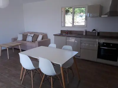 a kitchen and living room with a white table and chairs at gite tomasini sabrina zirilla in Monacia-dʼAullène